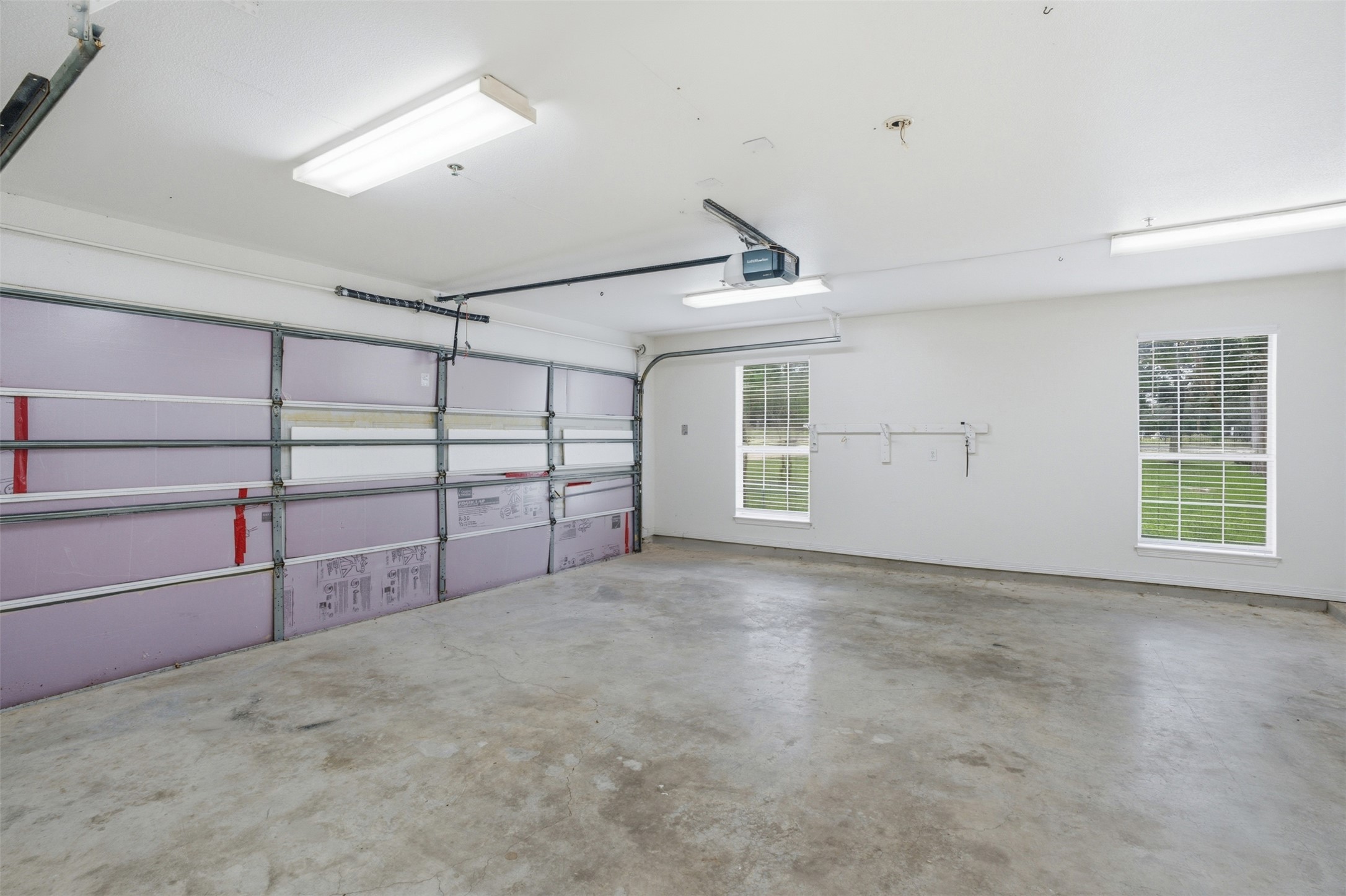 1301 County Road 262 Georgetown, TX 78633 - Photo 32 of 39 Spacious garage featuring a concrete floor, two windows with blinds, a garage door opener, and fluorescent lighting