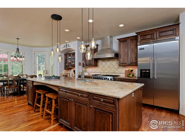 a kitchen with stainless steel appliances granite countertop a sink a stove and a refrigerator