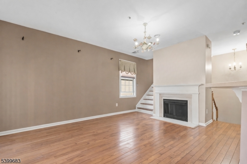 159 George Russell Way Clifton, NJ 07013 - Photo 6 of 25 an empty room with wooden floor fireplace cabinet and windows
