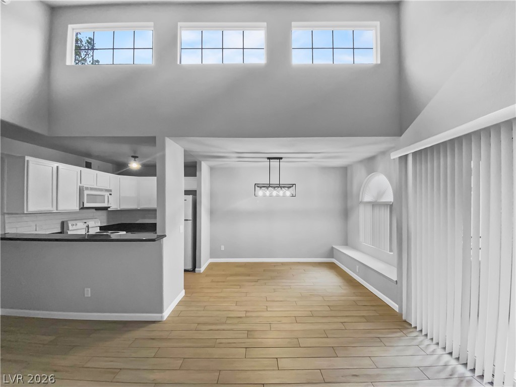 9325 West Desert Inn Road, Unit 278 Las Vegas, NV 89117 - Photo 2 of 17 A well-lit open-concept living area boasts high ceilings and stylish wood flooring, connecting seamlessly to a contemporary kitchen.
