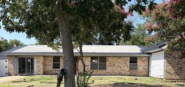 Single story home featuring brick siding, a front lawn, and a metal roof