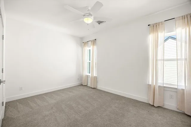 an empty room with a ceiling fan and a window