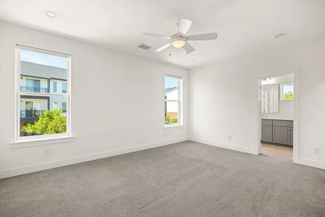 an empty room with windows and chandelier fan
