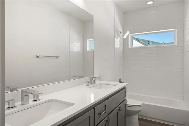 a bathroom with a granite countertop sink a toilet and shower