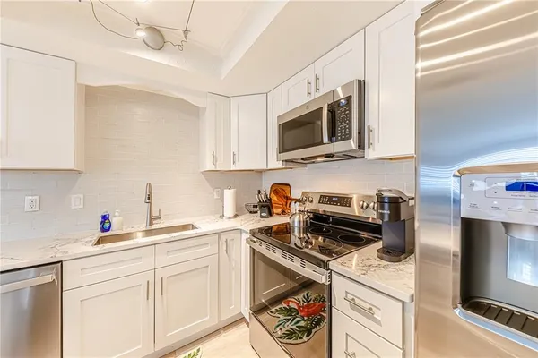 a kitchen with stainless steel appliances granite countertop a sink a stove a microwave and wooden cabinets