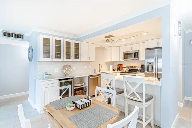 a open kitchen with stainless steel appliances granite countertop a stove top oven a sink a dining table and chairs with wooden floor