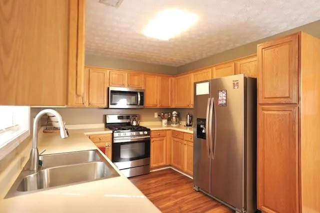 a kitchen with granite countertop a refrigerator stove and sink