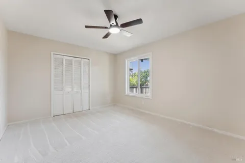 an empty room with a ceiling fan and window