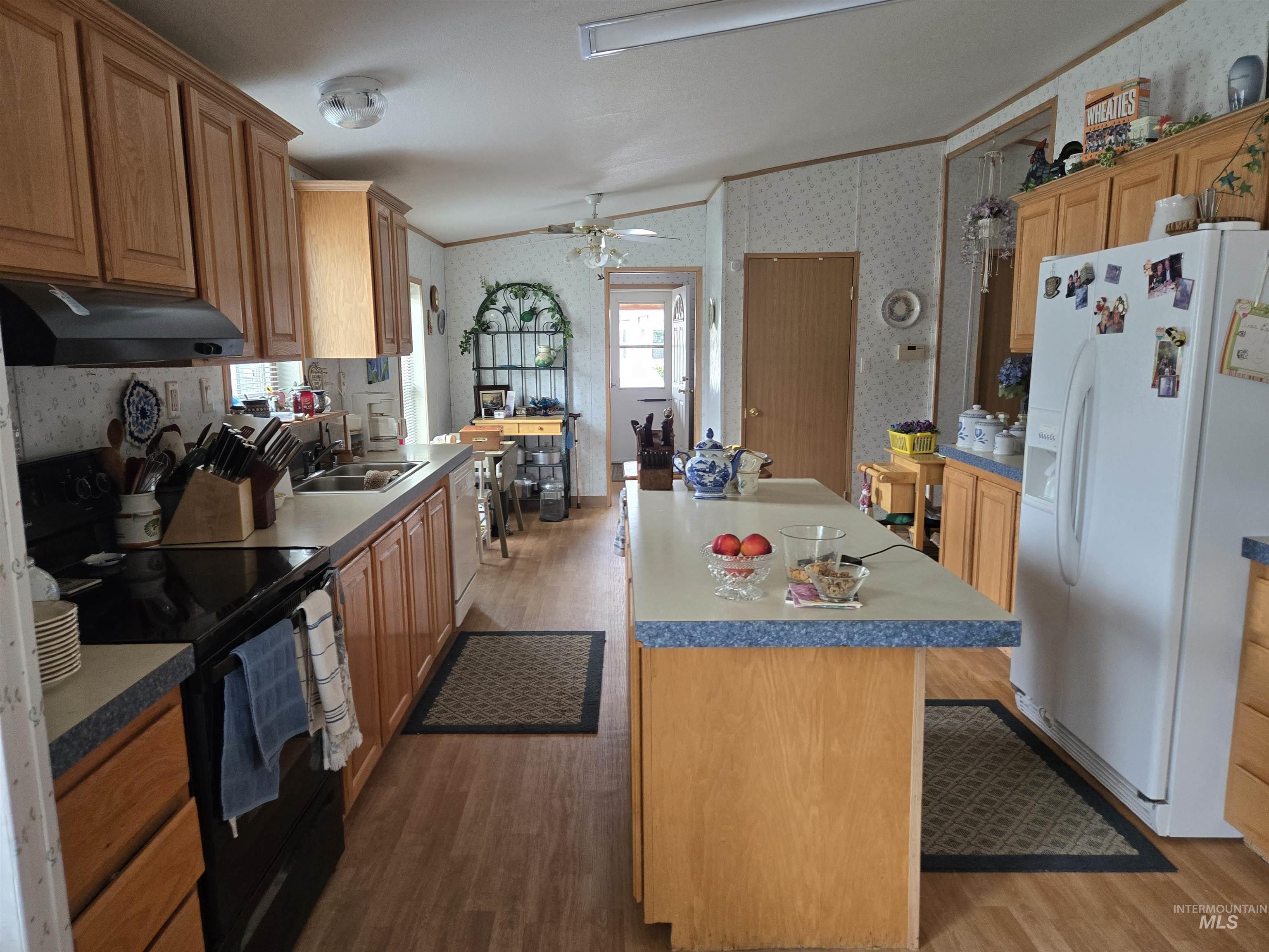 2750 Alden Road, Unit 37 Fruitland, ID 83619 - Photo 11 of 30 Kitchen with wallpapered walls, white appliances, wood finished floors, a center island, and under cabinet range hood