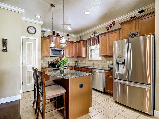a kitchen with stainless steel appliances granite countertop a dining table chairs refrigerator and microwave