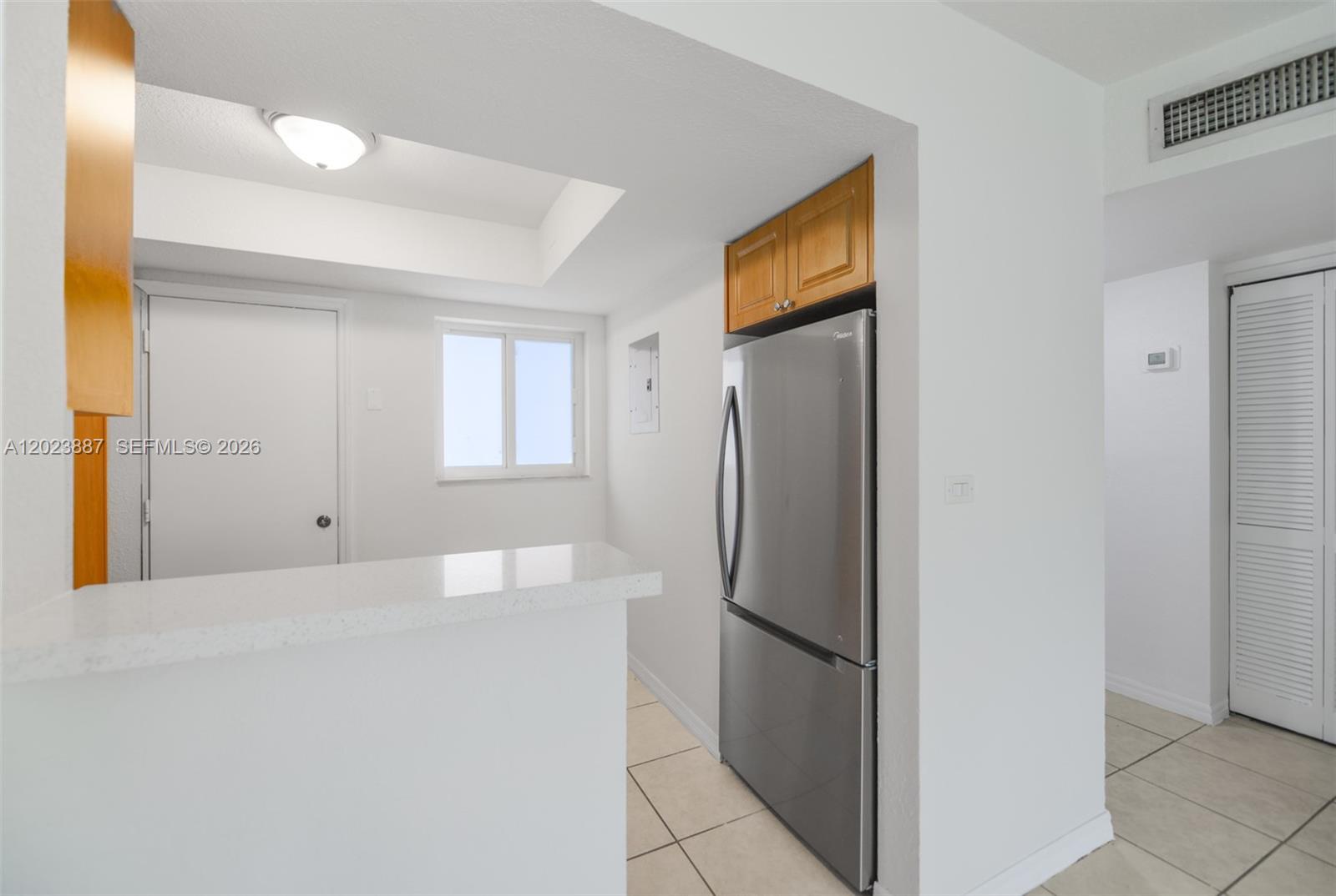 7737 Southwest 88th Street, Unit C312 Miami, FL 33156 - Photo 11 of 32 a view of a refrigerator in kitchen and an empty room