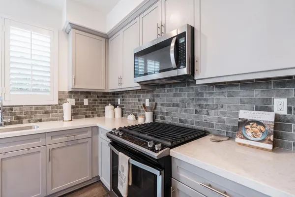 a kitchen with stainless steel appliances granite countertop white cabinets stove top oven and sink