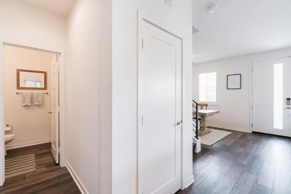 a view of a hallway with wooden floor and a bathroom