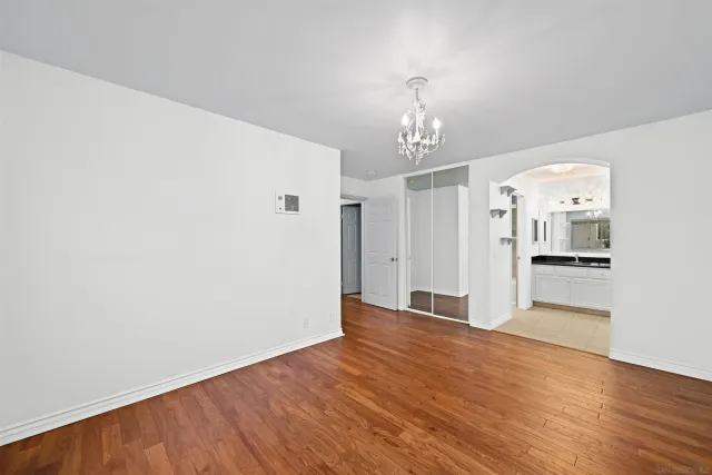 a view of a hallway with wooden floor and a kitchen
