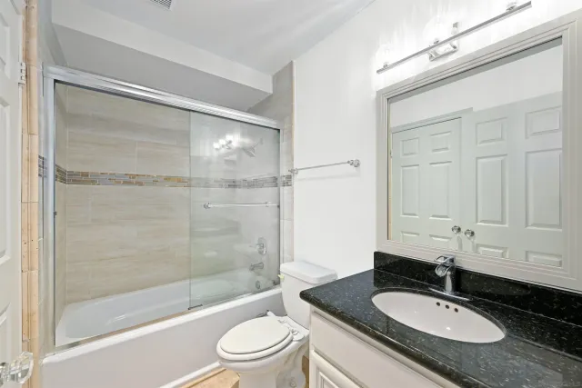 a bathroom with a granite countertop sink toilet and shower