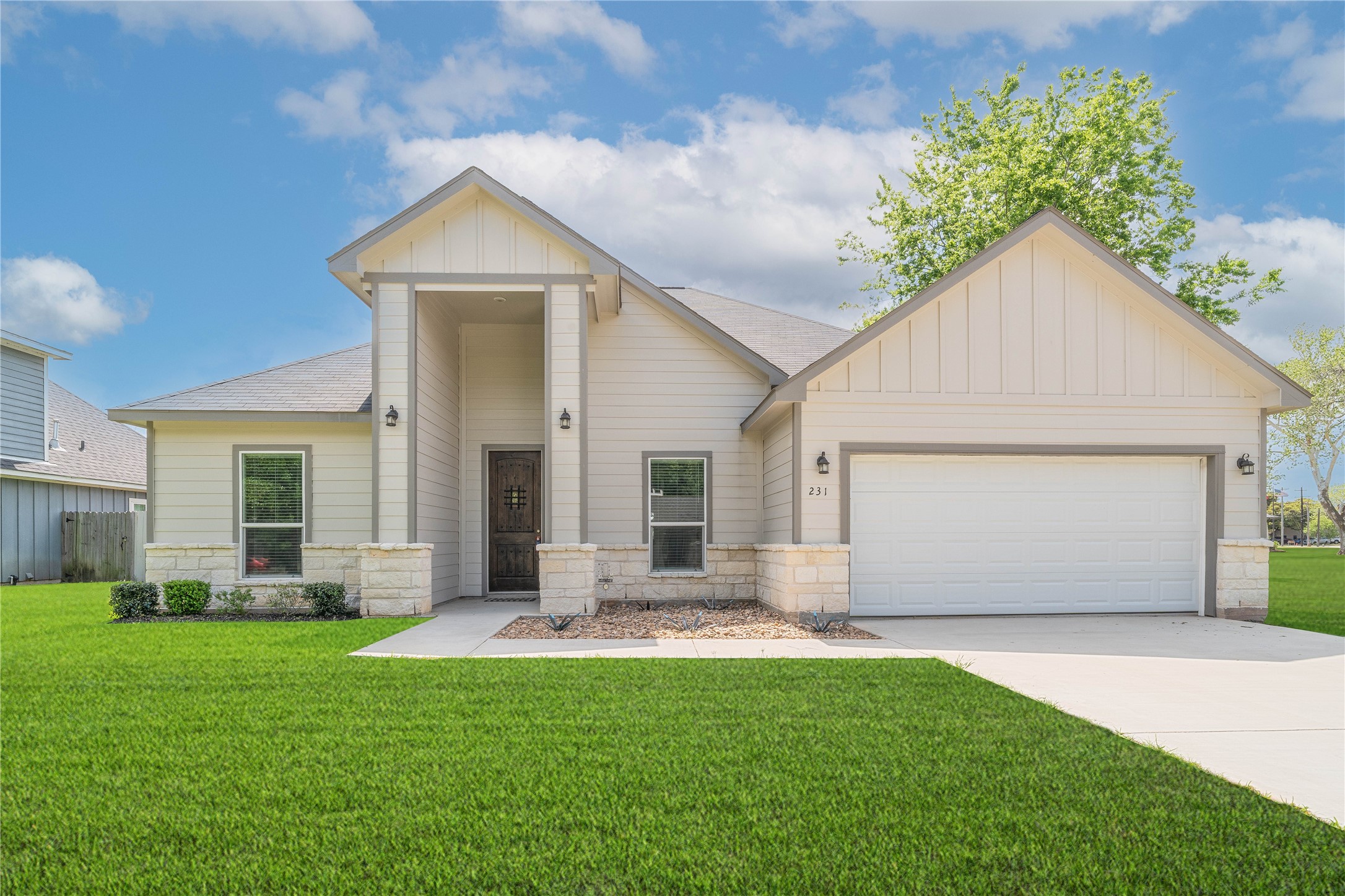 231 McCormick Street Columbus, TX 78934 - Photo 1 of 27 Front Exterior – Attractive front elevation with a welcoming covered entry, stone accents, and a two-car garage.