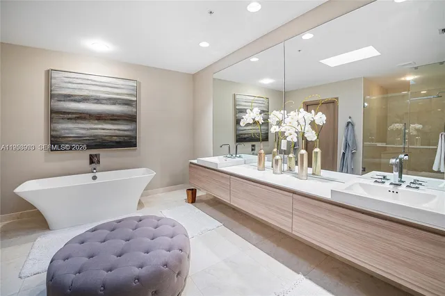 a bathroom with a double vanity sink a mirror and bathtub