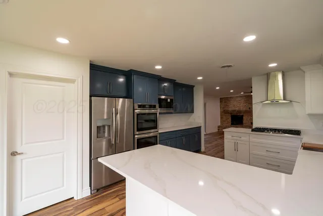 a kitchen with stainless steel appliances kitchen island granite countertop a refrigerator and a stove top oven