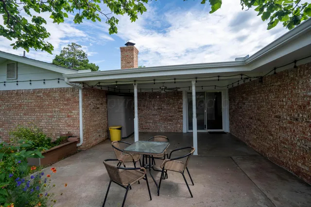a backyard of a house with table and chairs plants and large tree