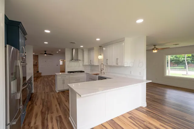 a view of a kitchen with kitchen island a sink wooden floor and a refrigerator