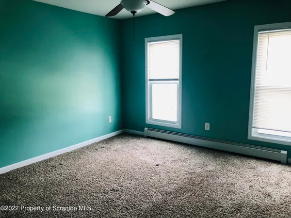 a view of an empty room with a window and a kitchen