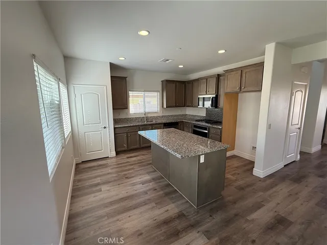 a kitchen with stainless steel appliances granite countertop a refrigerator a sink dishwasher a stove and a refrigerator with wooden floor