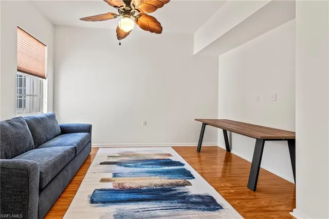 a view of a swimming pool with outdoor seating space and trees in the background
