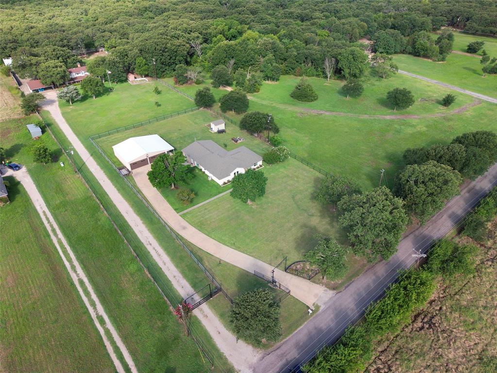380 Farr Altom Road Seagoville, TX 75159 - Photo 27 of 30 Expansive rural property featuring a main residence with a light-colored roof, a large detached outbuilding with multiple garage doors, and extensive green space with mature trees