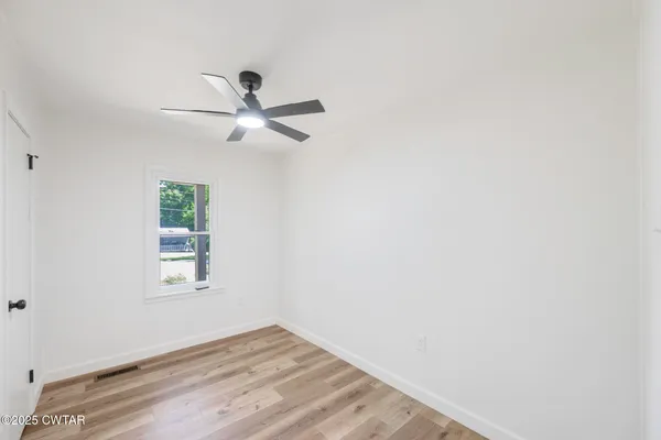 an empty room with a window and a ceiling fan