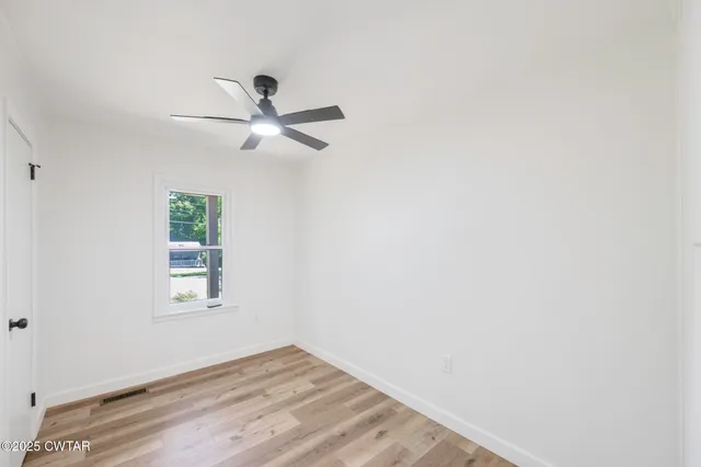 an empty room with a window and a ceiling fan
