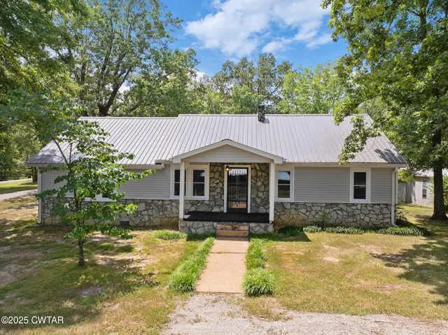 a front view of a house with a yard and trees
