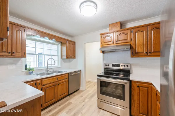 a large living room with stainless steel appliances granite countertop a sink dishwasher stove and wooden cabinets