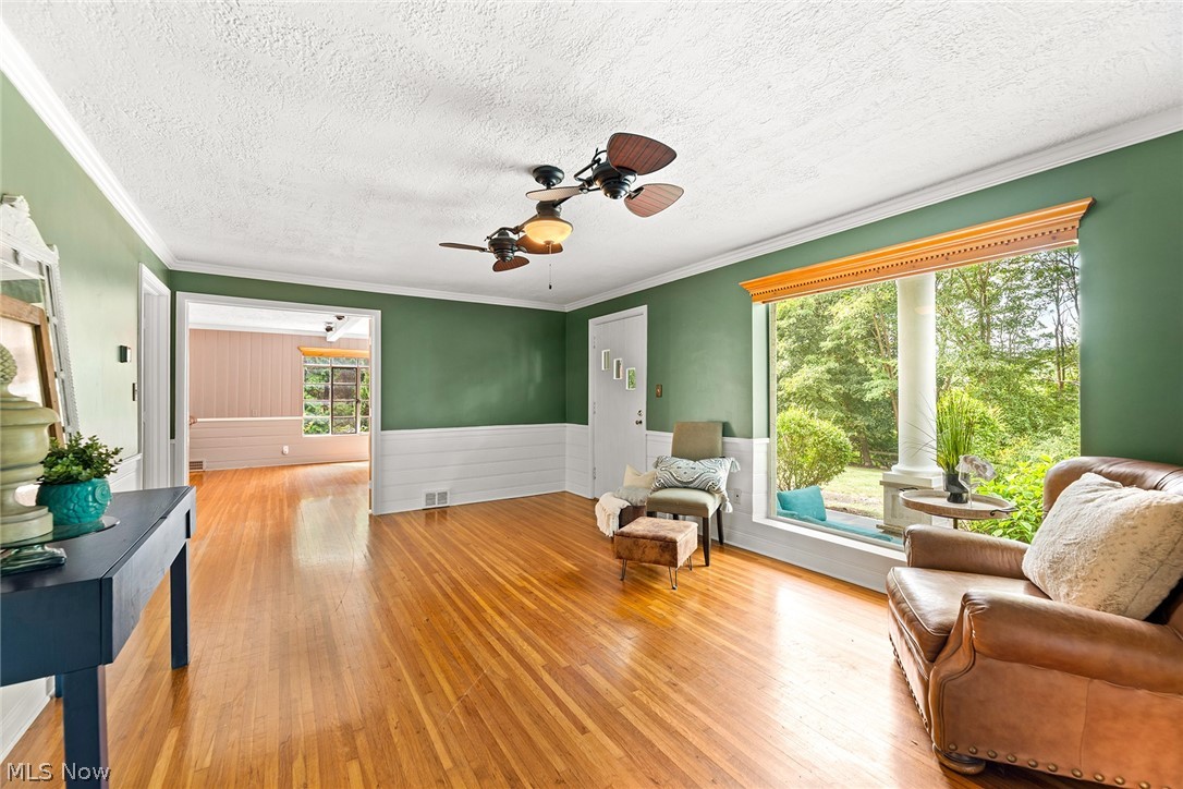 1375 North Revere Road Akron, OH 44333 - Photo 18 of 50 Hardwood flooring, decorative ceiling fans, a large picture window with a built-in window seat, and white wall paneling