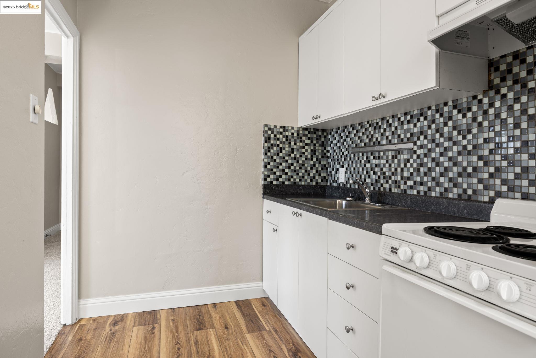 631 O'Farrell Street, Unit 416 San Francisco, CA 94109 - Photo 25 of 30 a kitchen with white cabinets and a stove