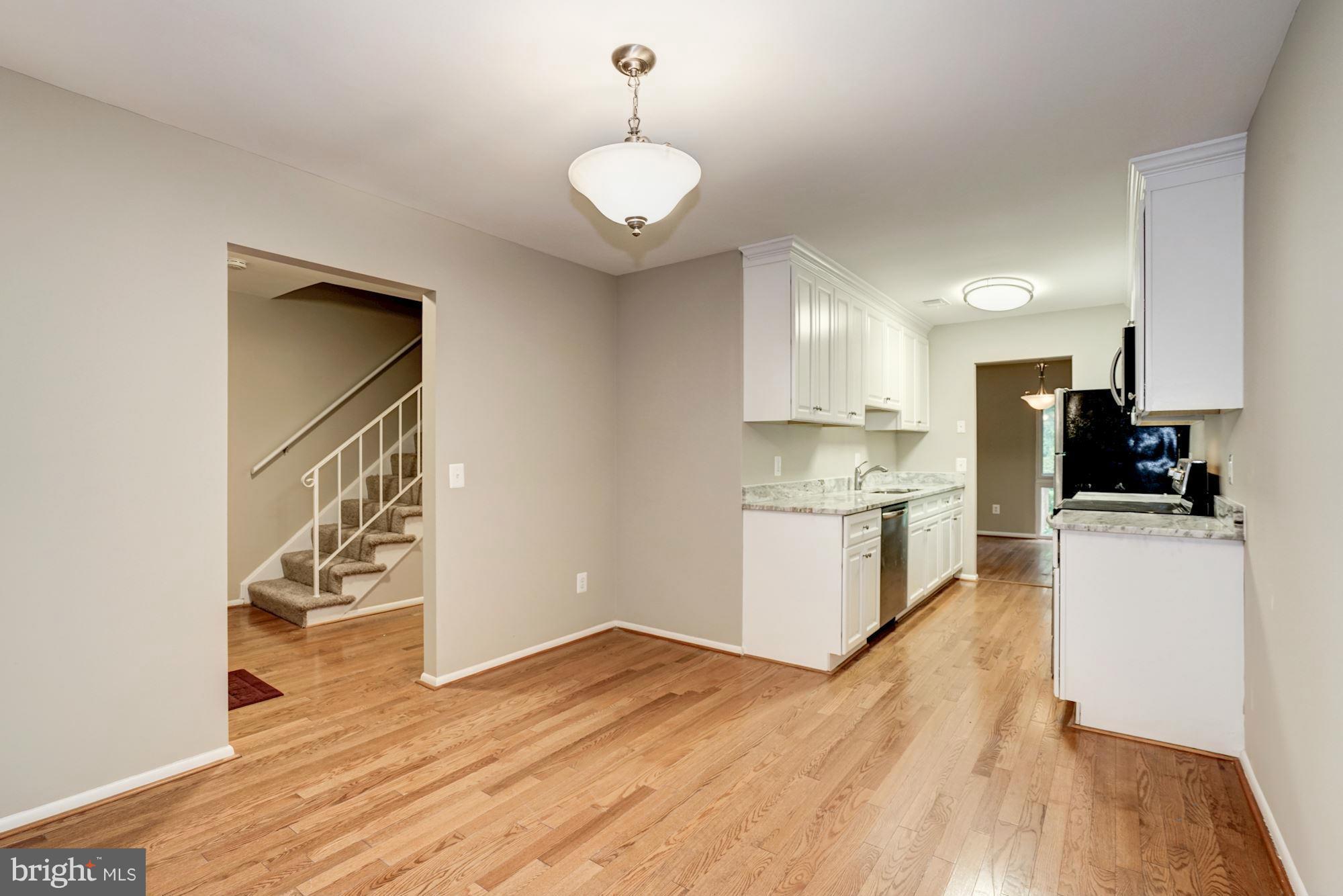 11704 Decade Court Reston, VA 20191 - Photo 5 of 30 a kitchen with granite countertop wooden floors and white cabinets