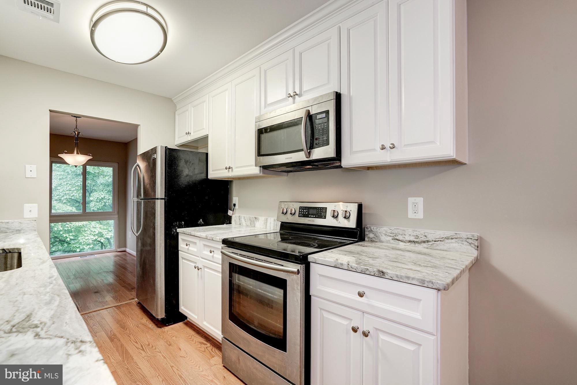 11704 Decade Court Reston, VA 20191 - Photo 7 of 30 a kitchen with granite countertop wooden cabinets stainless steel appliances and a window