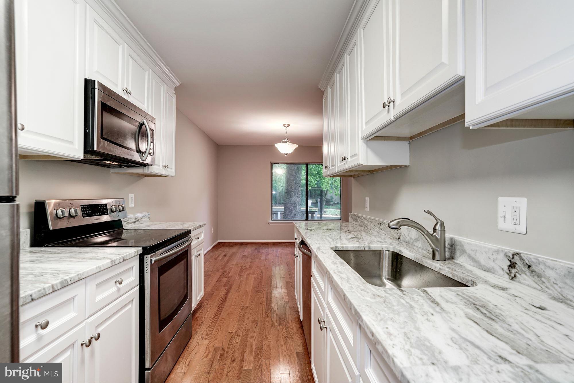 11704 Decade Court Reston, VA 20191 - Photo 10 of 30 a kitchen with stainless steel appliances granite countertop a sink dishwasher stove and microwave with wooden floor