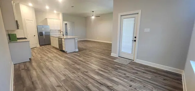 a view of empty room with wooden floor and ceiling fan