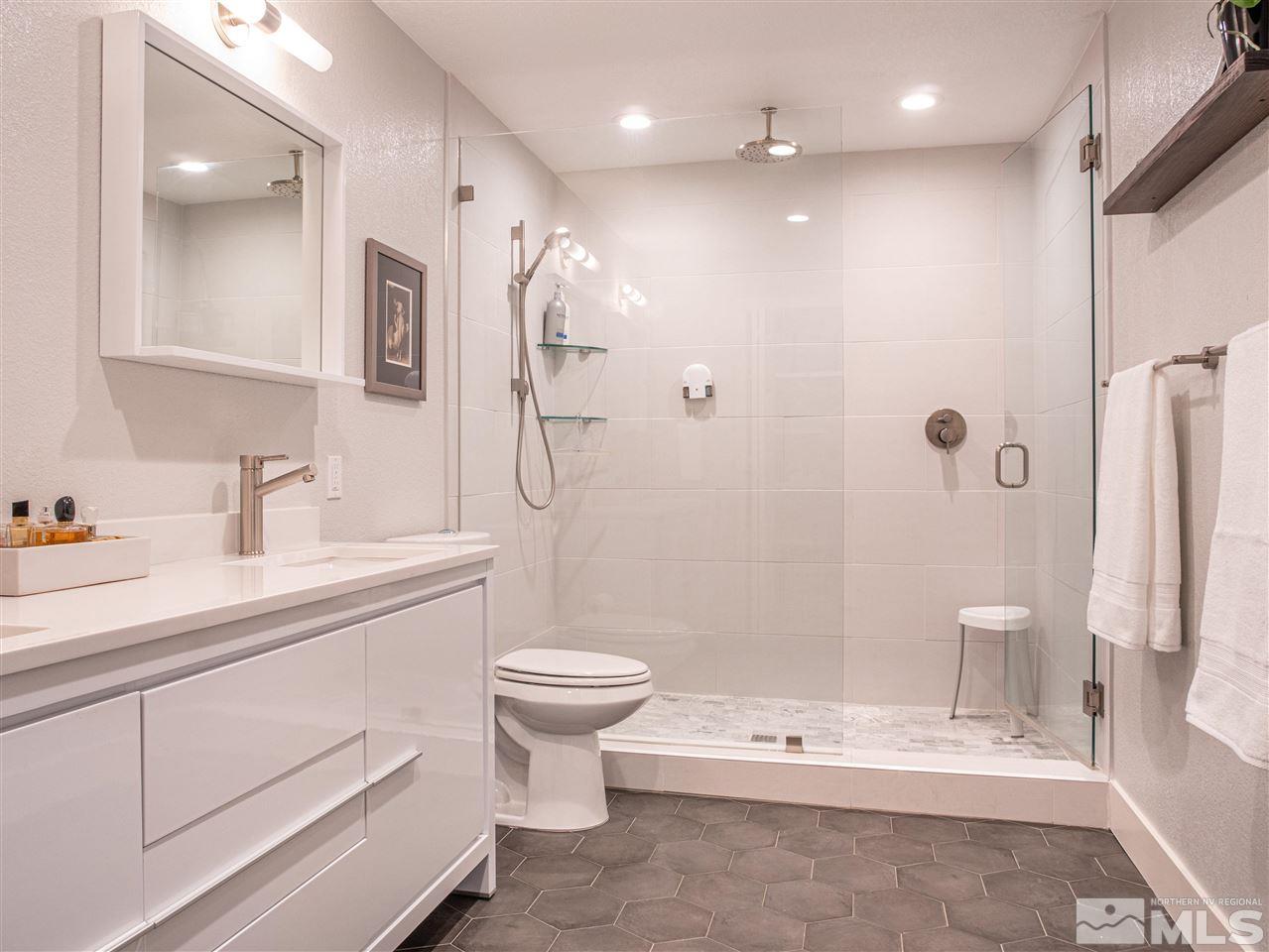 2435 Foley Way Reno, NV 89509 - Photo 20 of 32 a bathroom with a double vanity sink toilet a large mirror a shower and bathtub