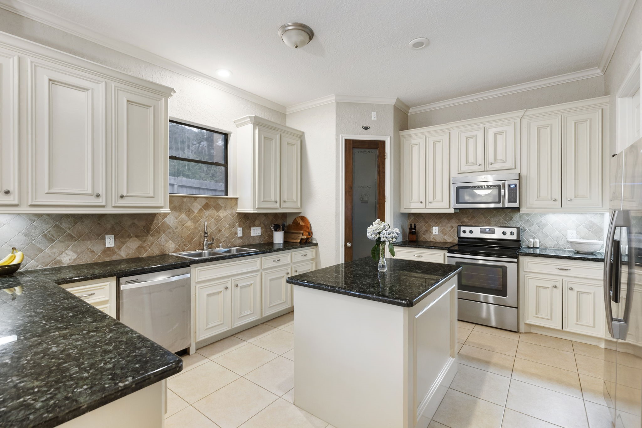 1898 Longmire Road, Unit 8 Conroe, TX 77304 - Photo 7 of 26 a kitchen with granite countertop white cabinets and stainless steel appliances