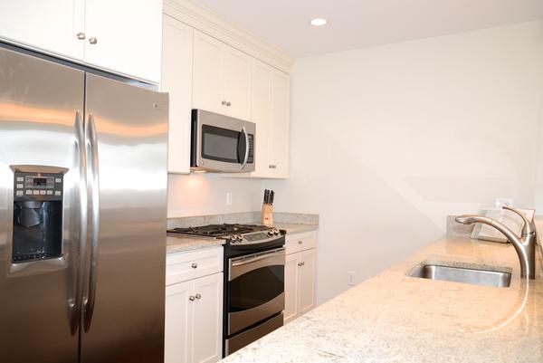 116-128 Rantoul Street, Unit 507 Beverly, MA 01915 - Photo 5 of 13 a kitchen with stainless steel appliances granite countertop a refrigerator a stove and a sink with wooden floor