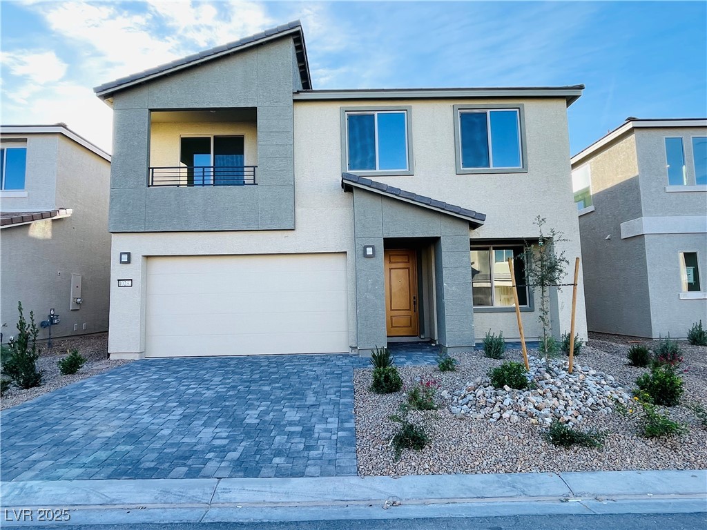 Contemporary house featuring stucco siding, decorative driveway, and a balcony