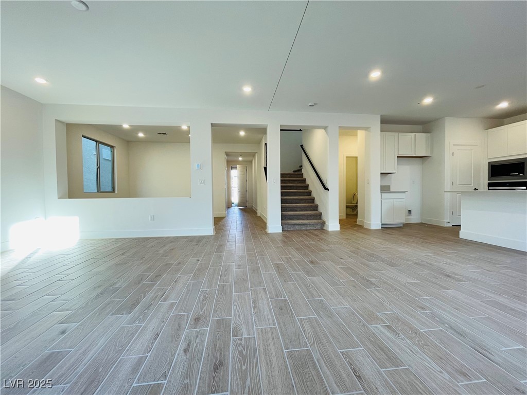 10237 Mystic Falls Drive Las Vegas, NV 89141 - Photo 4 of 23 Unfurnished living room featuring wood finish floors, stairway, and recessed lighting