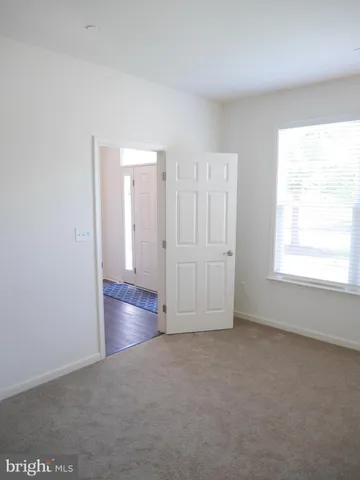 an empty room with chandelier fan and windows