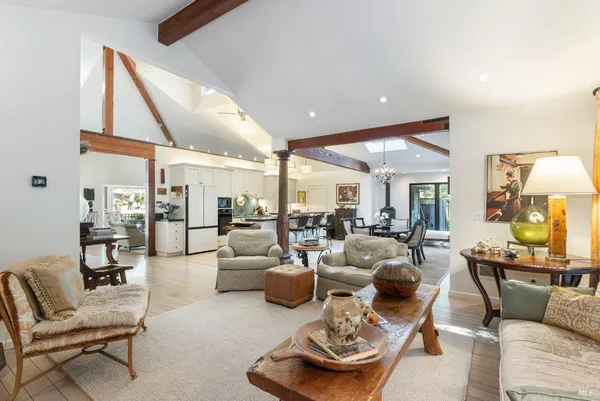 a living room with lots of furniture kitchen view and a large window