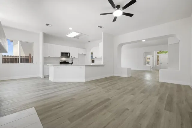 an empty room with wooden floor and a ceiling fan