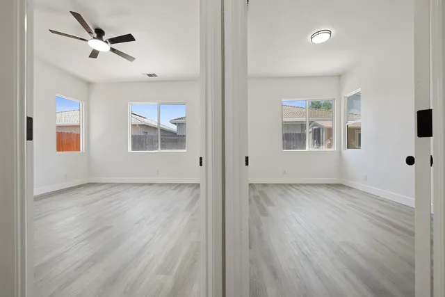 a view of an empty room with a window and wooden floor
