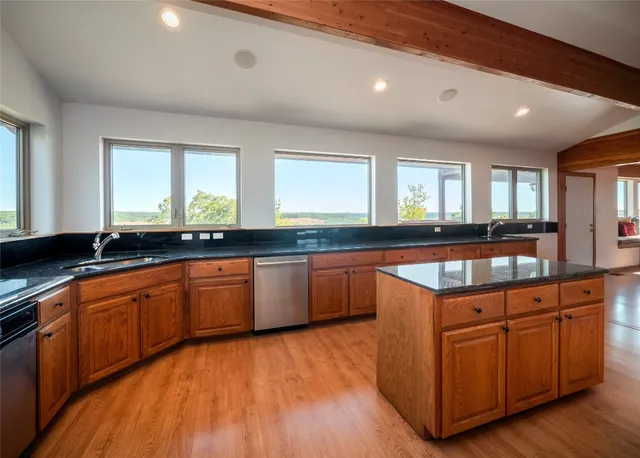 a kitchen with stainless steel appliances granite countertop a stove a sink dishwasher and a microwave oven on the wooden floor