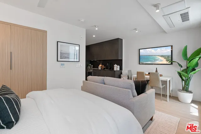 a bedroom with a large bed couch and a potted plant