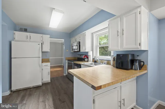 a kitchen with granite countertop a refrigerator a stove a sink dishwasher and a refrigerator with wooden floor